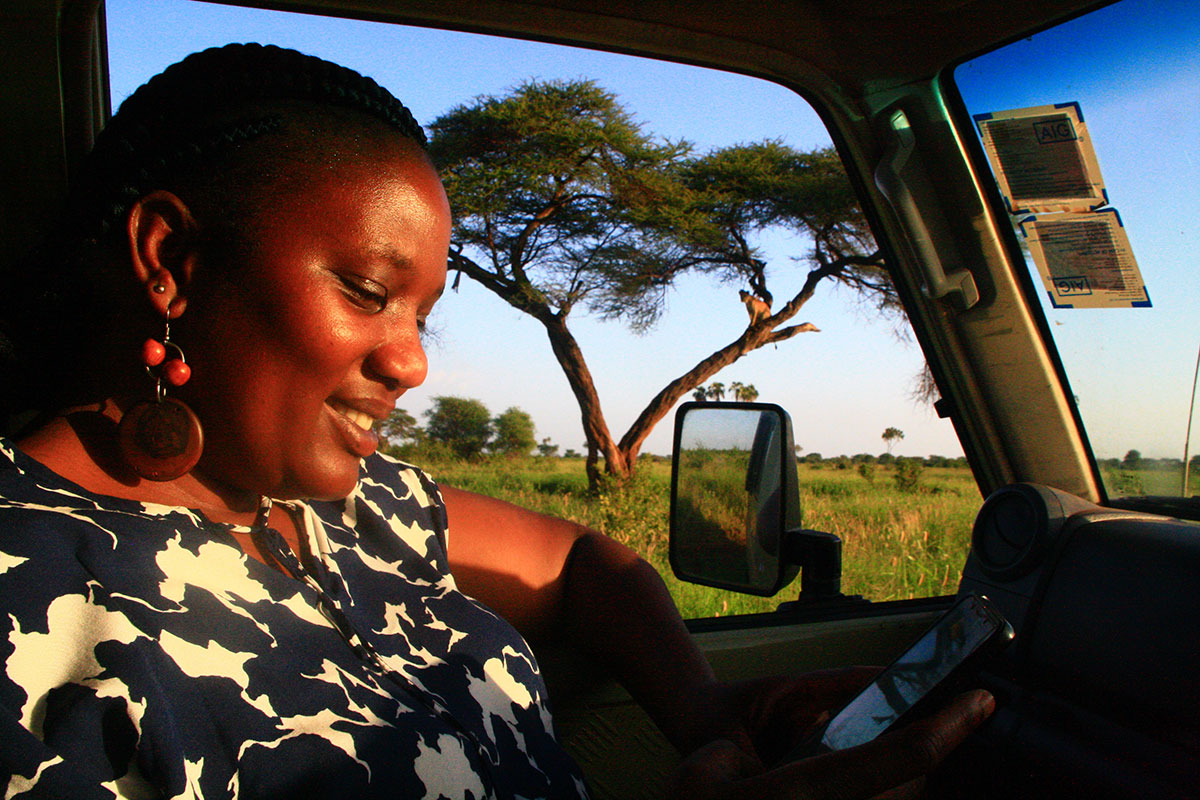 A photograph of Dr. Caroline Ng’weno In her vehicle on the African savanna, documenting a Lion sighting. 